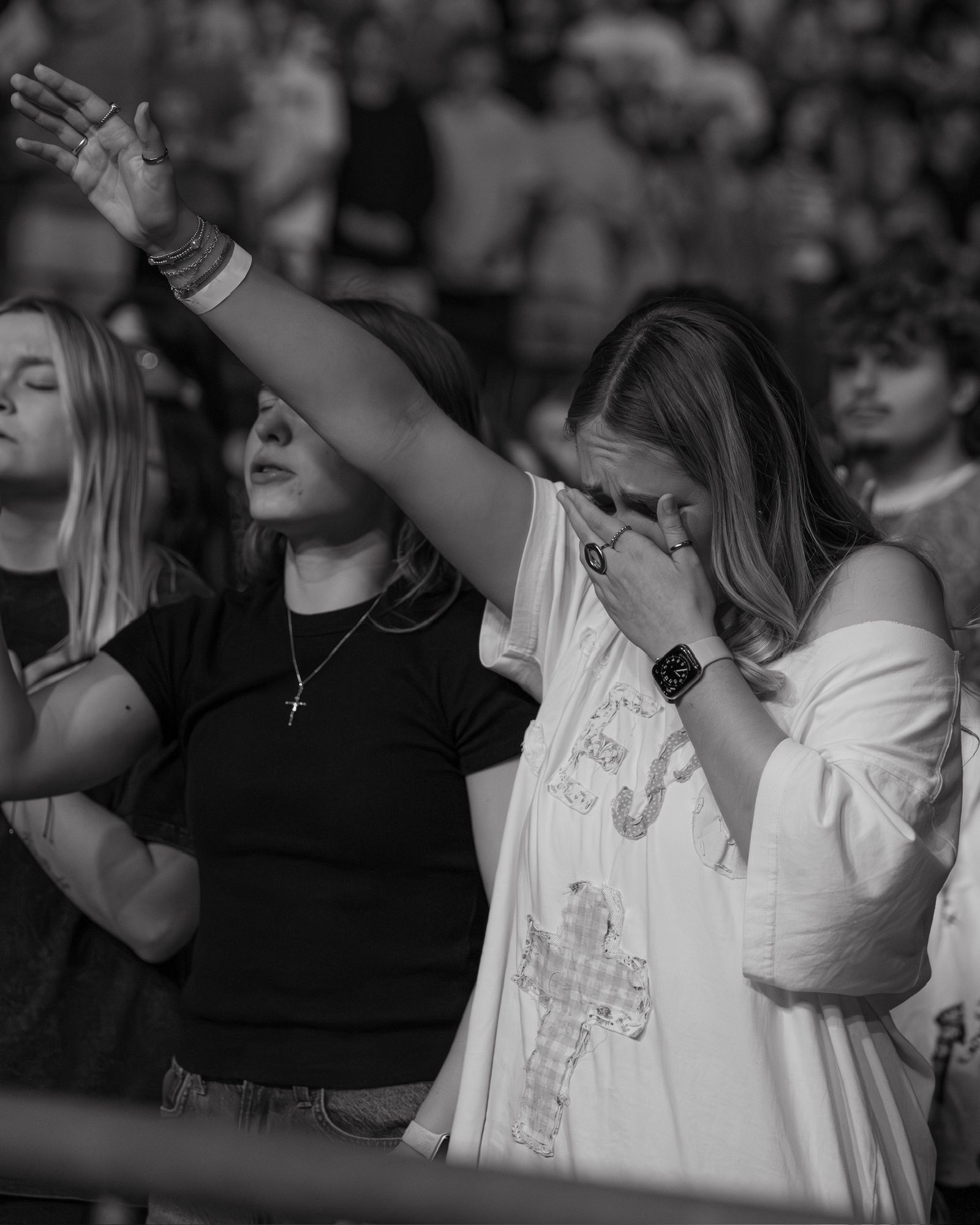 Two students in worship, one with her hand pressed over her face